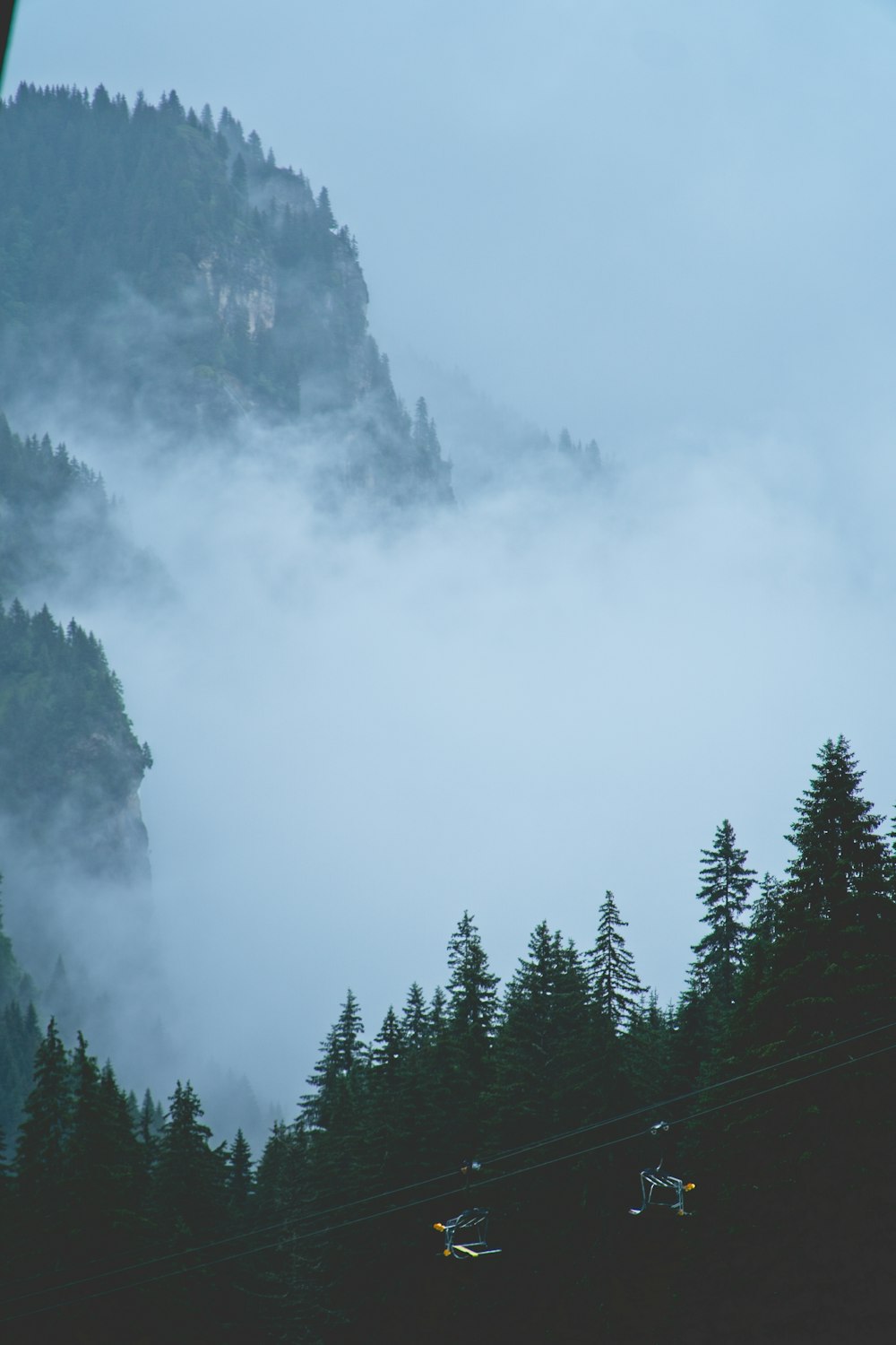 un telesilla subiendo a una montaña cubierta de niebla