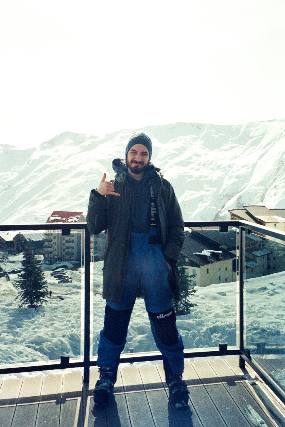 a man standing on top of a balcony next to a snow covered mountain