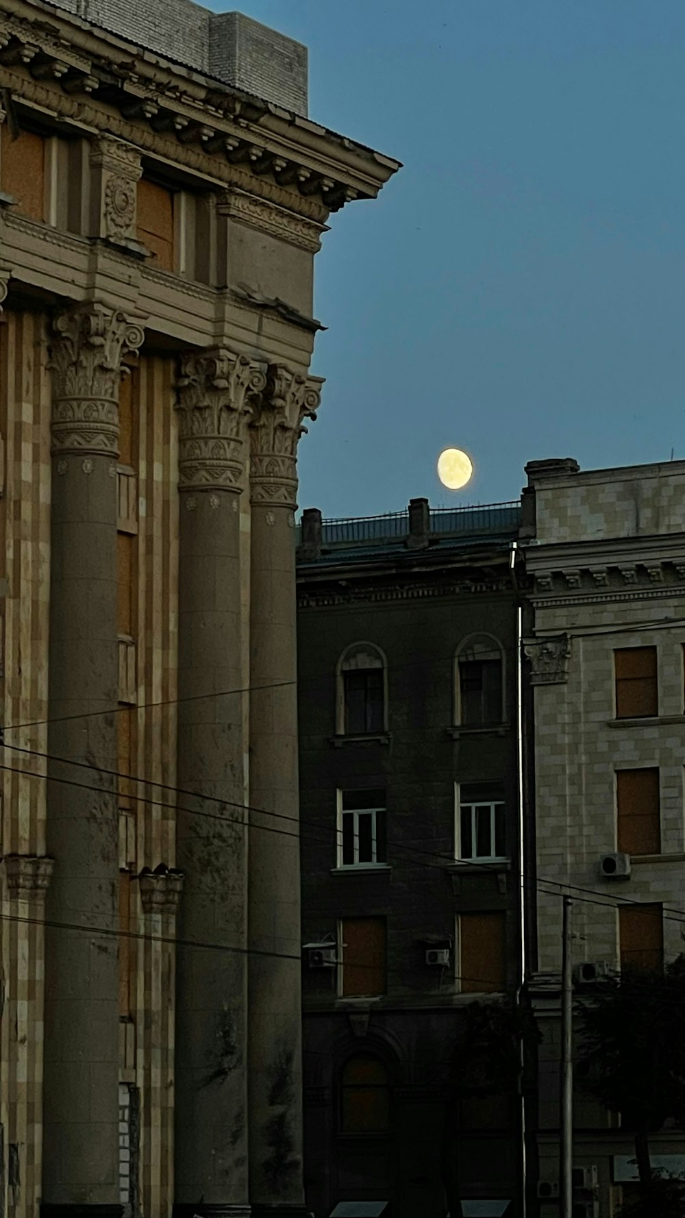 a full moon is seen behind a building