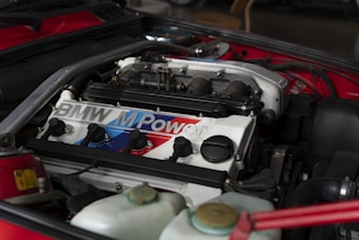 the engine compartment of a red sports car showing car battery sold in tyrepublic nigeria