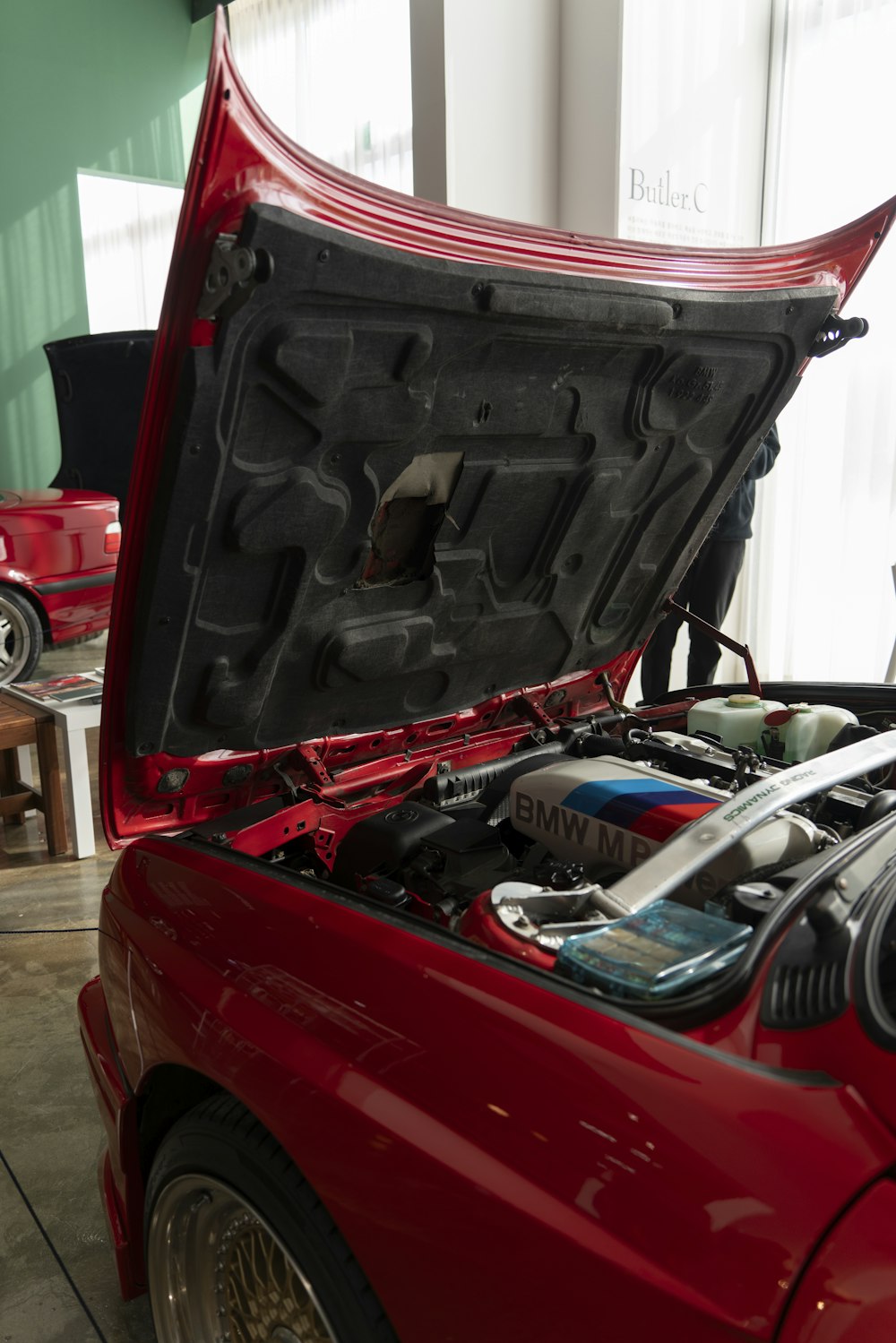 a red car with its hood open in a garage
