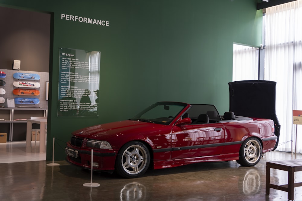 a red convertible car parked in front of a green wall