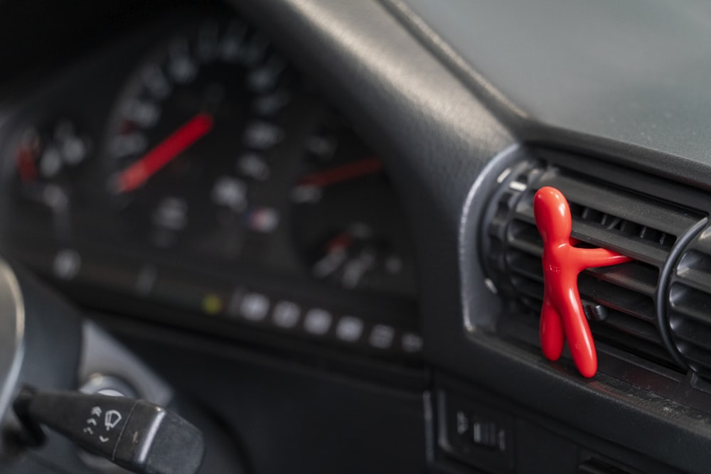 a close up of a car dashboard with a red object on the dashboard