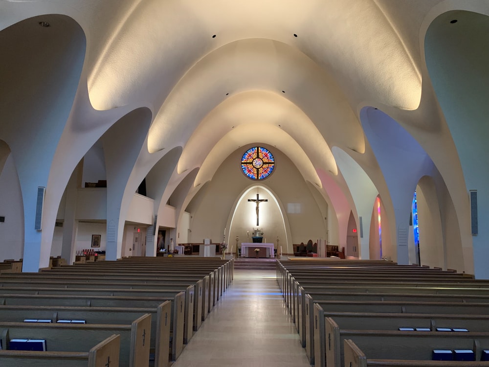 das Innere einer Kirche mit Kirchenbänken und einem Buntglasfenster