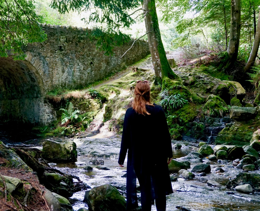a woman standing in a stream in the woods