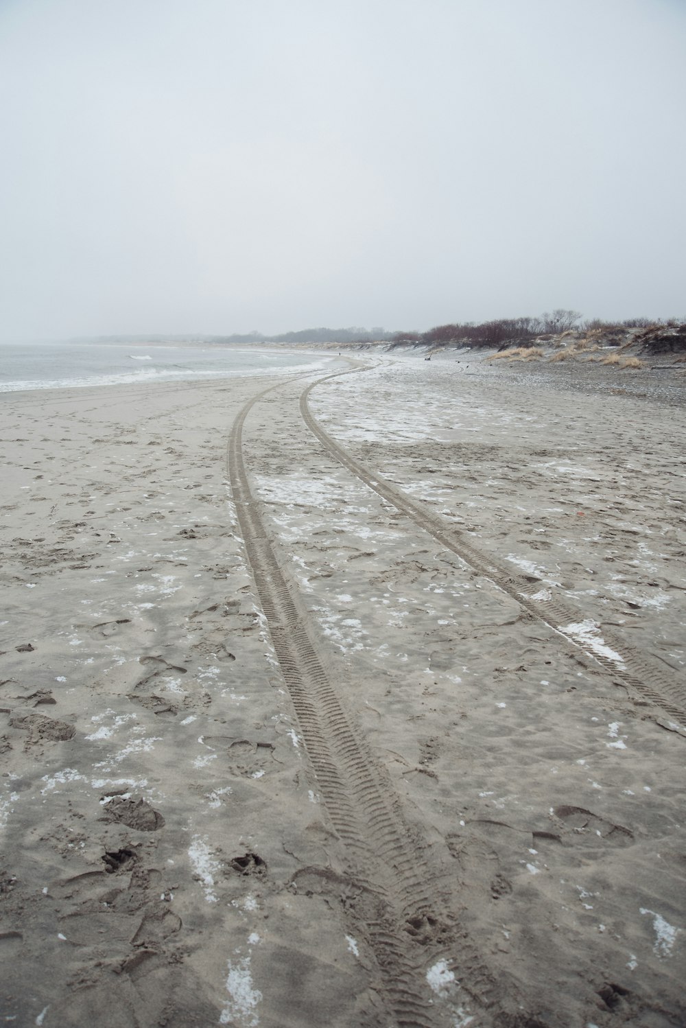 a sandy beach with tracks in the sand