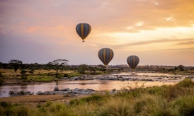 three hot air balloons flying over a river