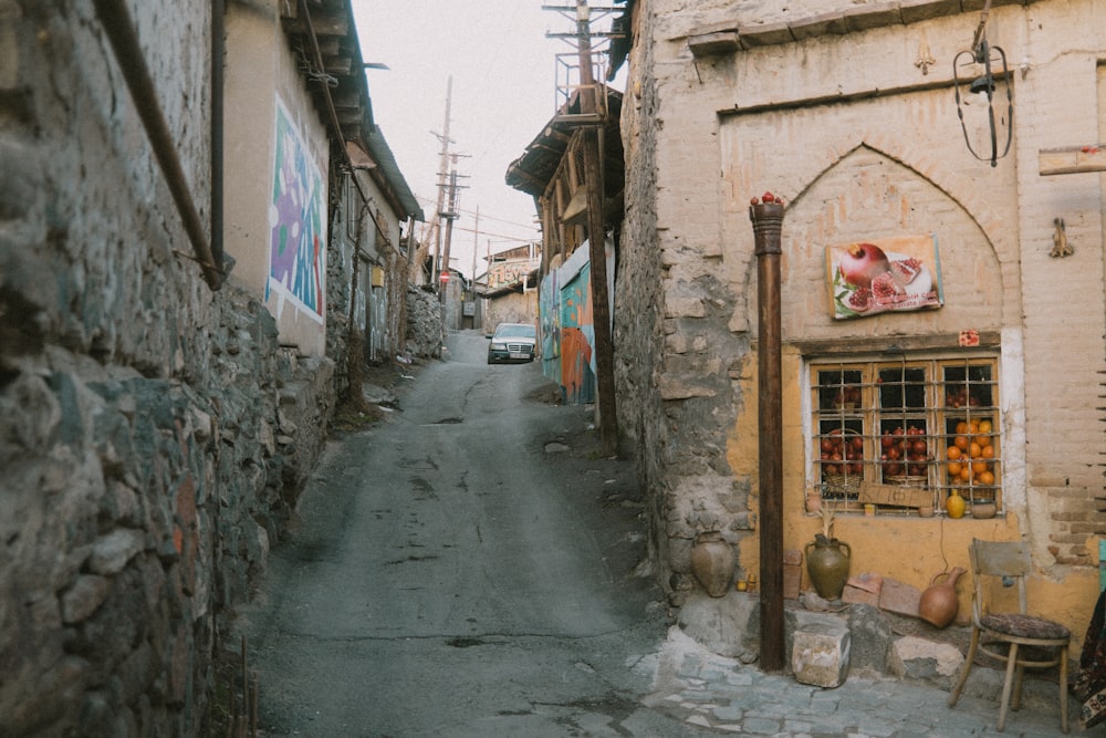 a narrow street with a car parked on the side of it