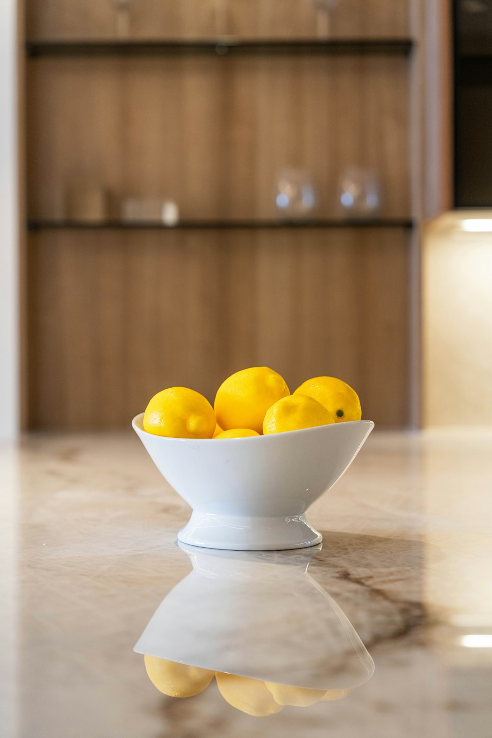 a white bowl filled with lemons on top of a counter