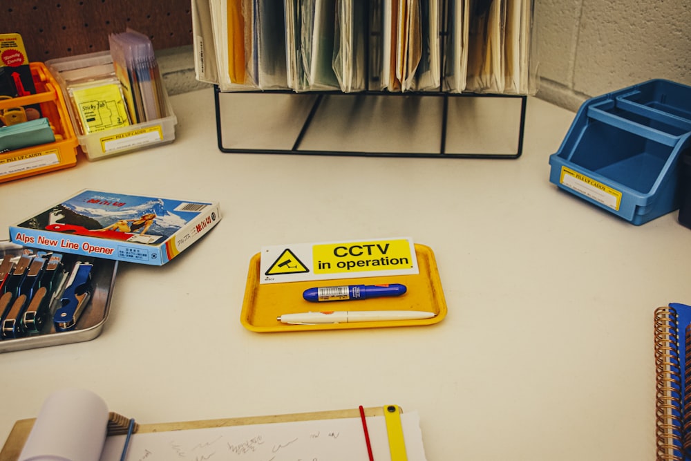 un escritorio cubierto con un letrero amarillo y mucho material de oficina