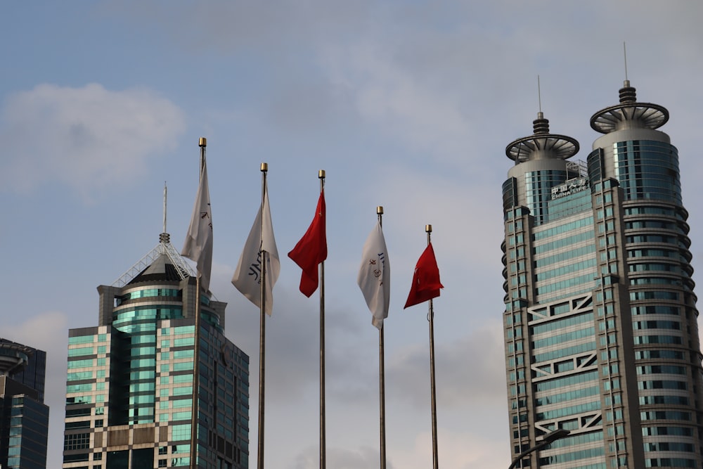 a group of flags flying in front of tall buildings