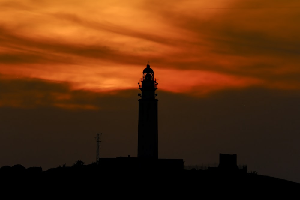 una torre de reloj recortada contra el cielo de una puesta de sol