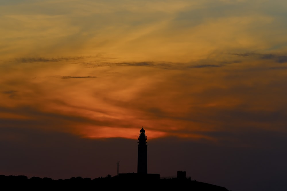 Il sole sta tramontando dietro una torre con un orologio