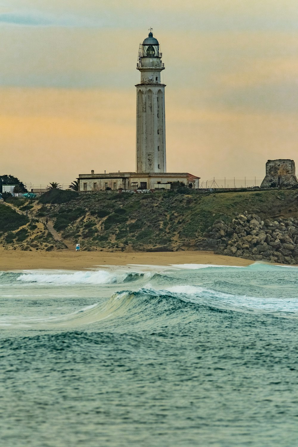 a lighthouse on top of a hill next to the ocean