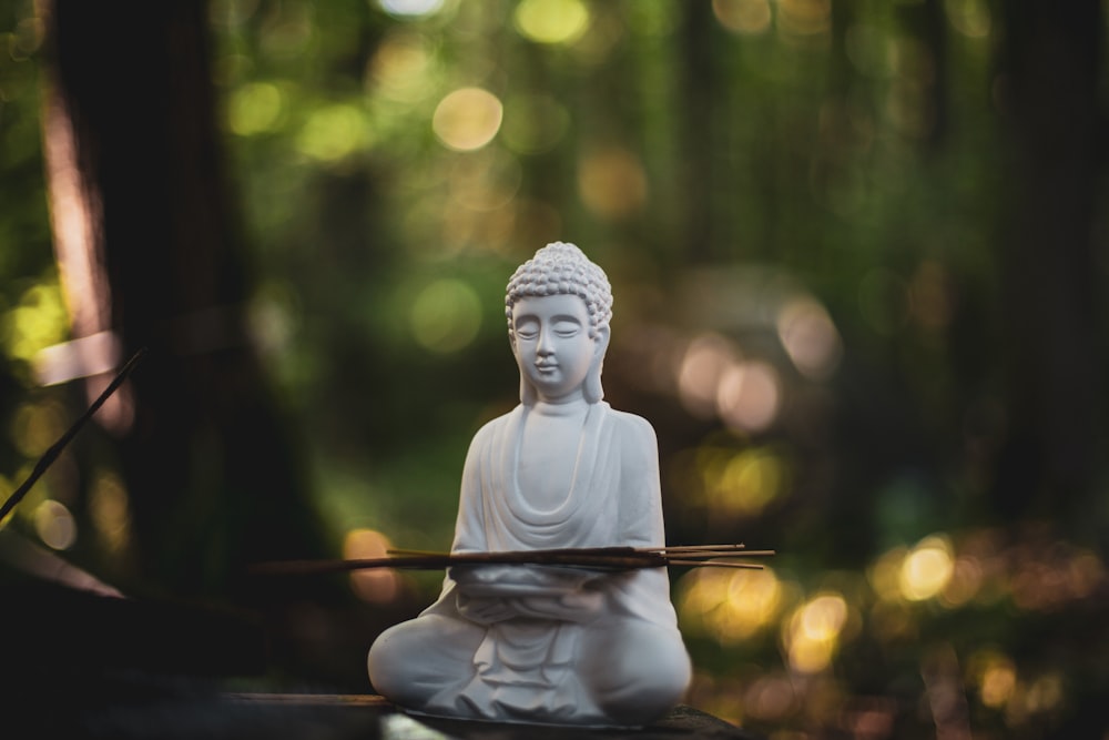 a white buddha statue sitting on top of a wooden table