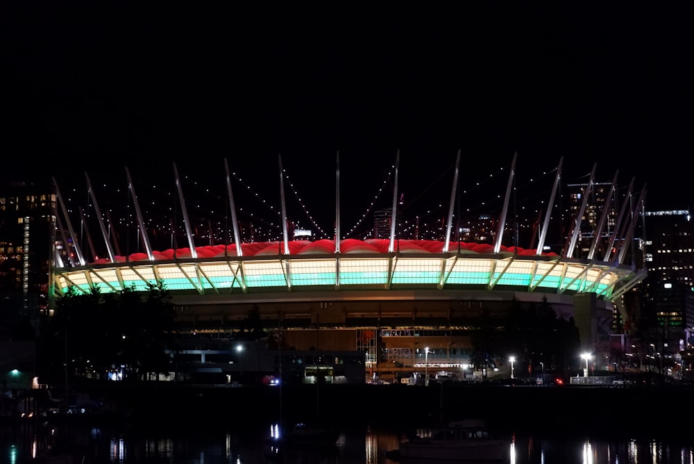 a stadium lit up at night with lights reflecting in the water