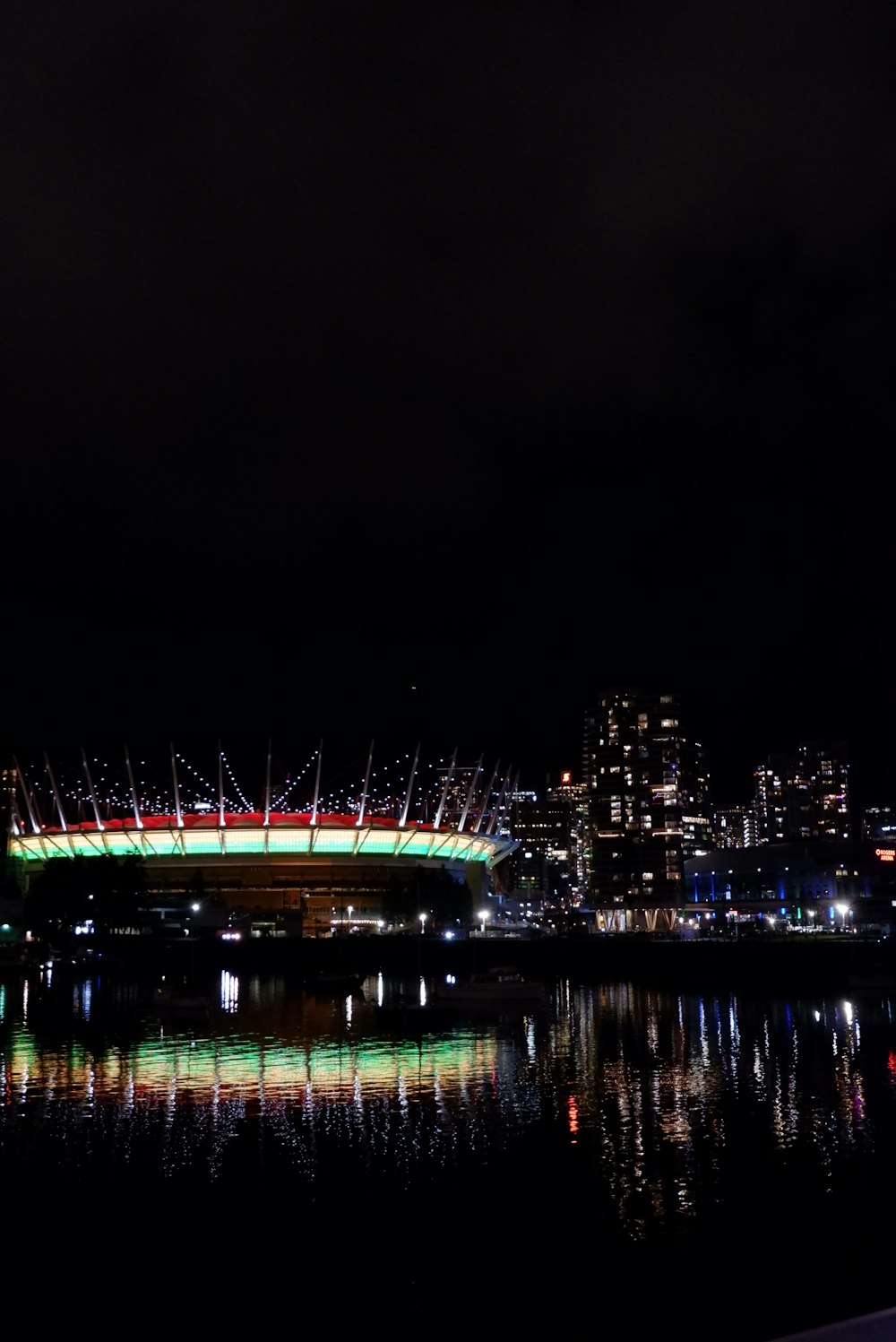 a stadium lit up at night with lights reflecting in the water