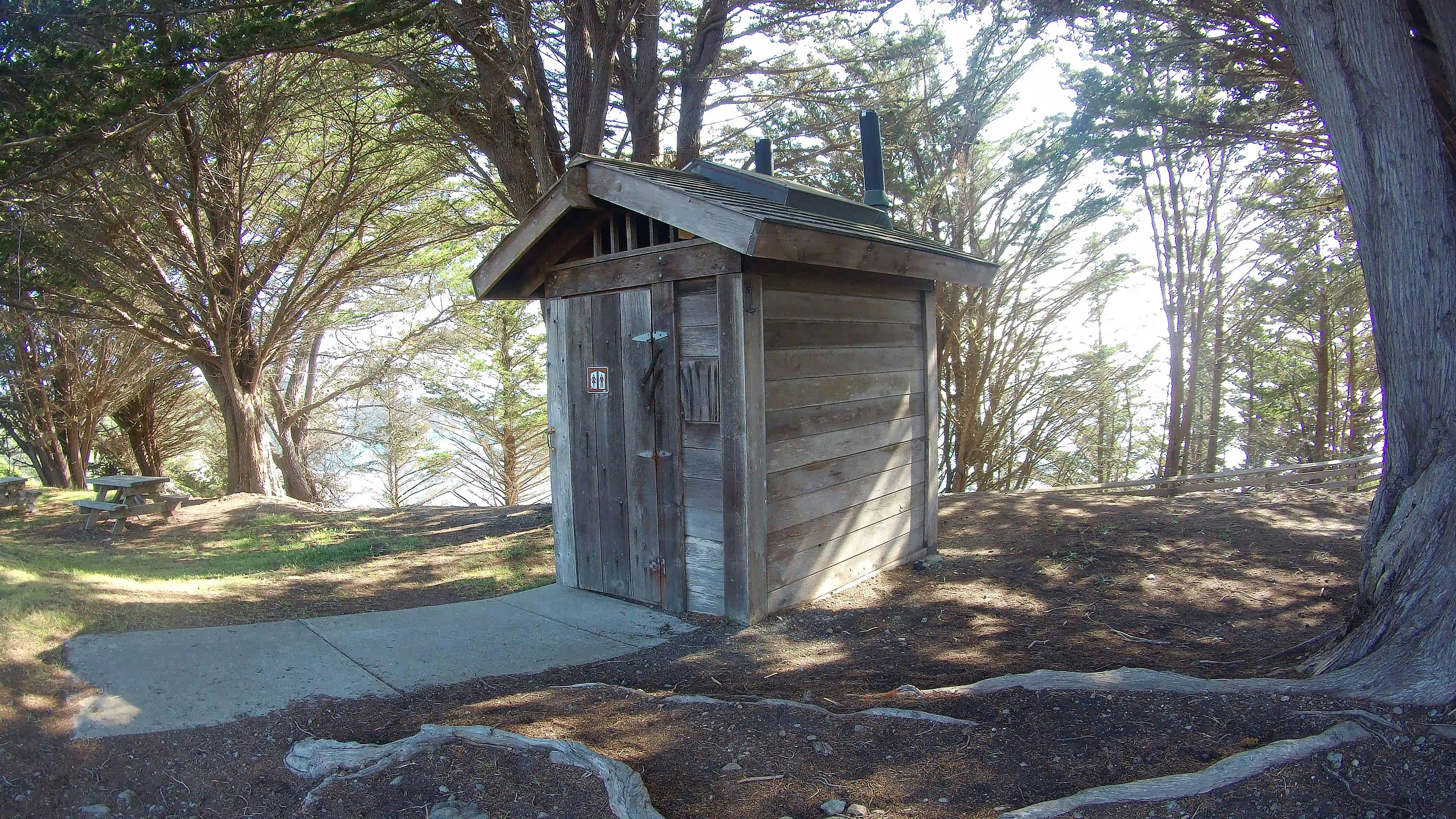a small outhouse in the middle of a wooded area