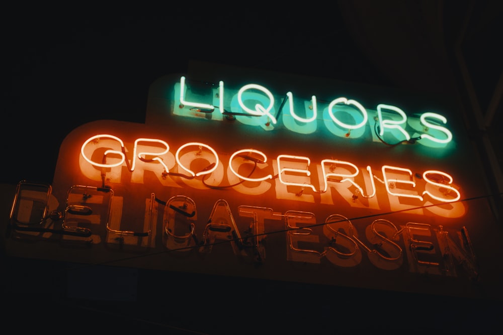 a neon sign that says liquors groceries deli