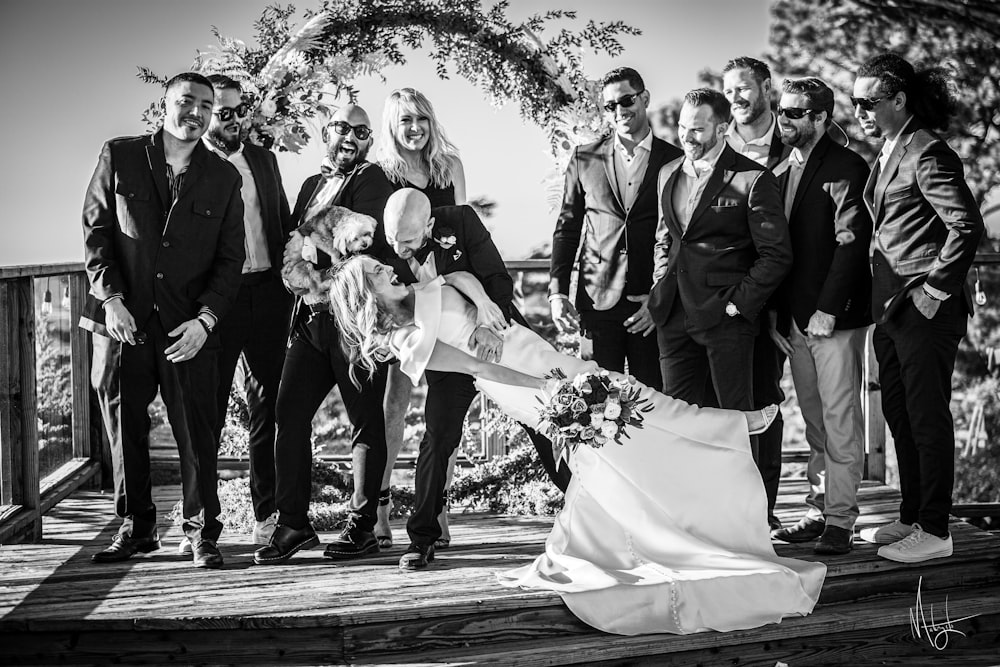 a group of people standing around a bride and groom