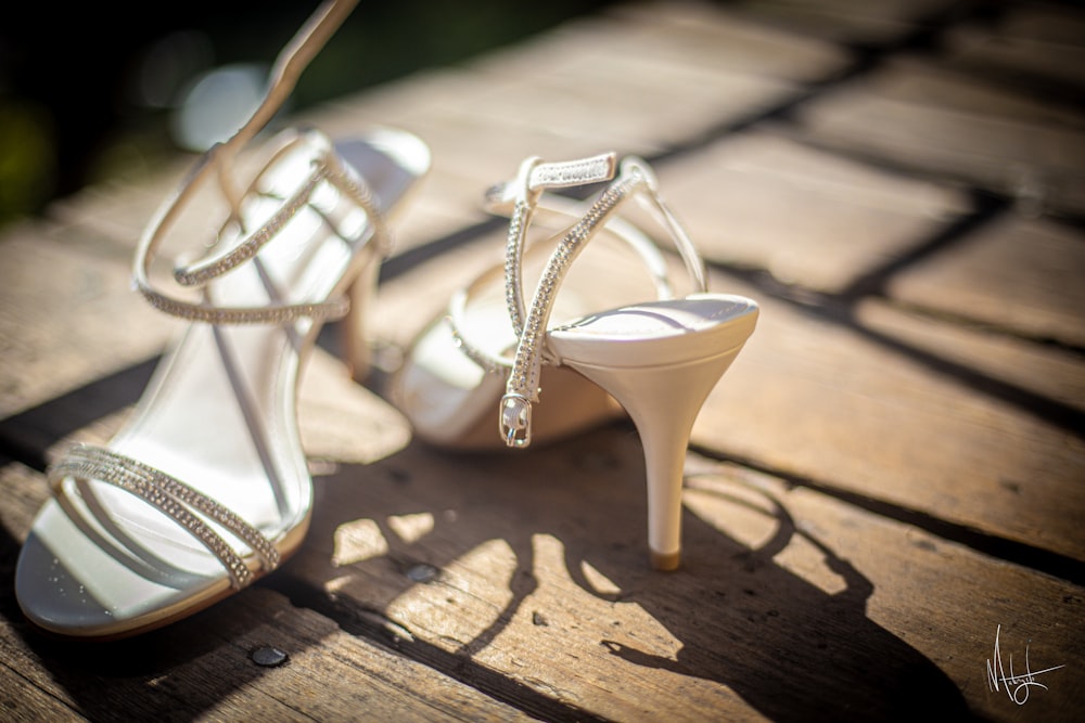 a pair of white high heeled shoes sitting on top of a wooden table