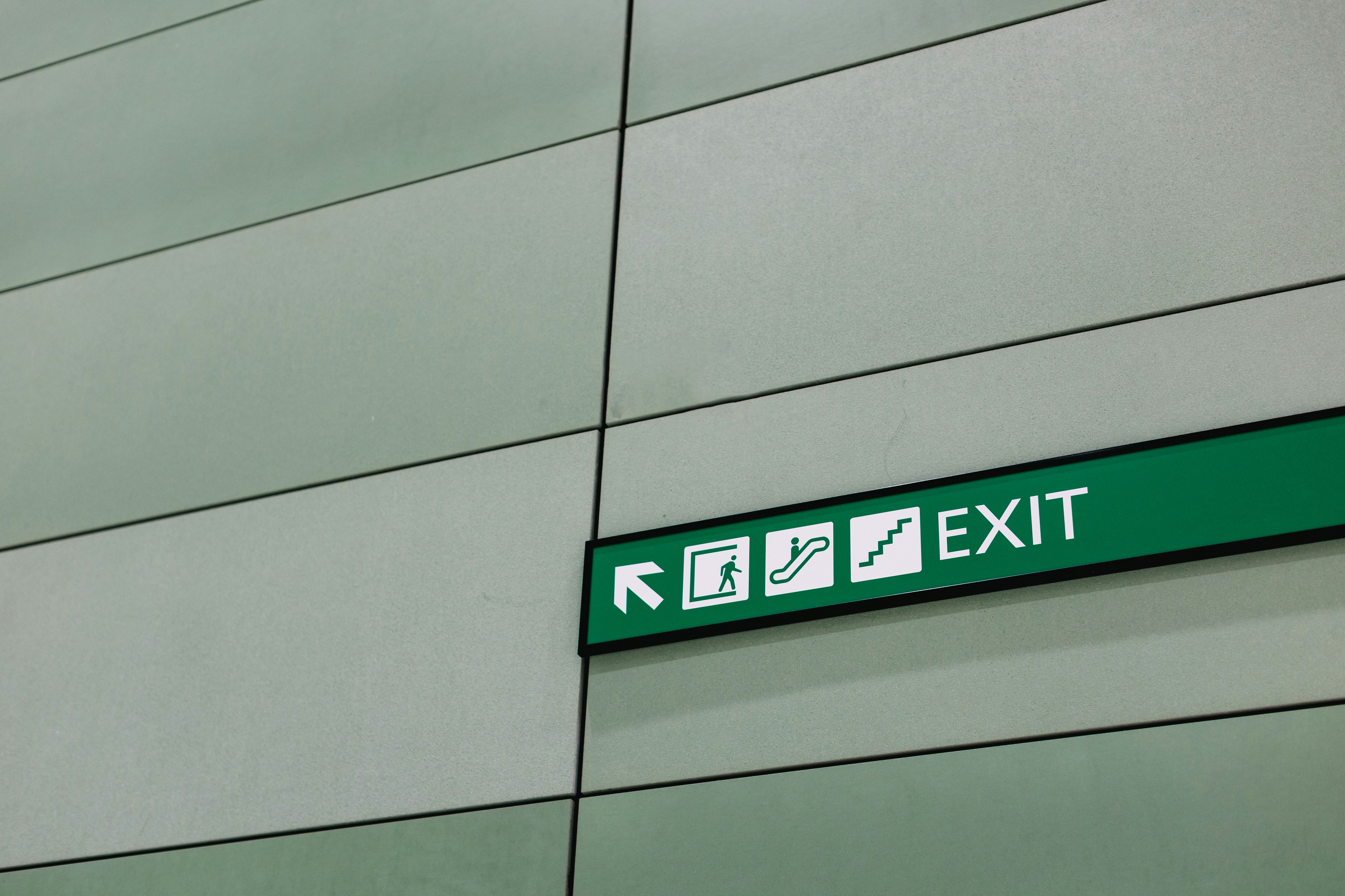a green exit sign mounted to the side of a building