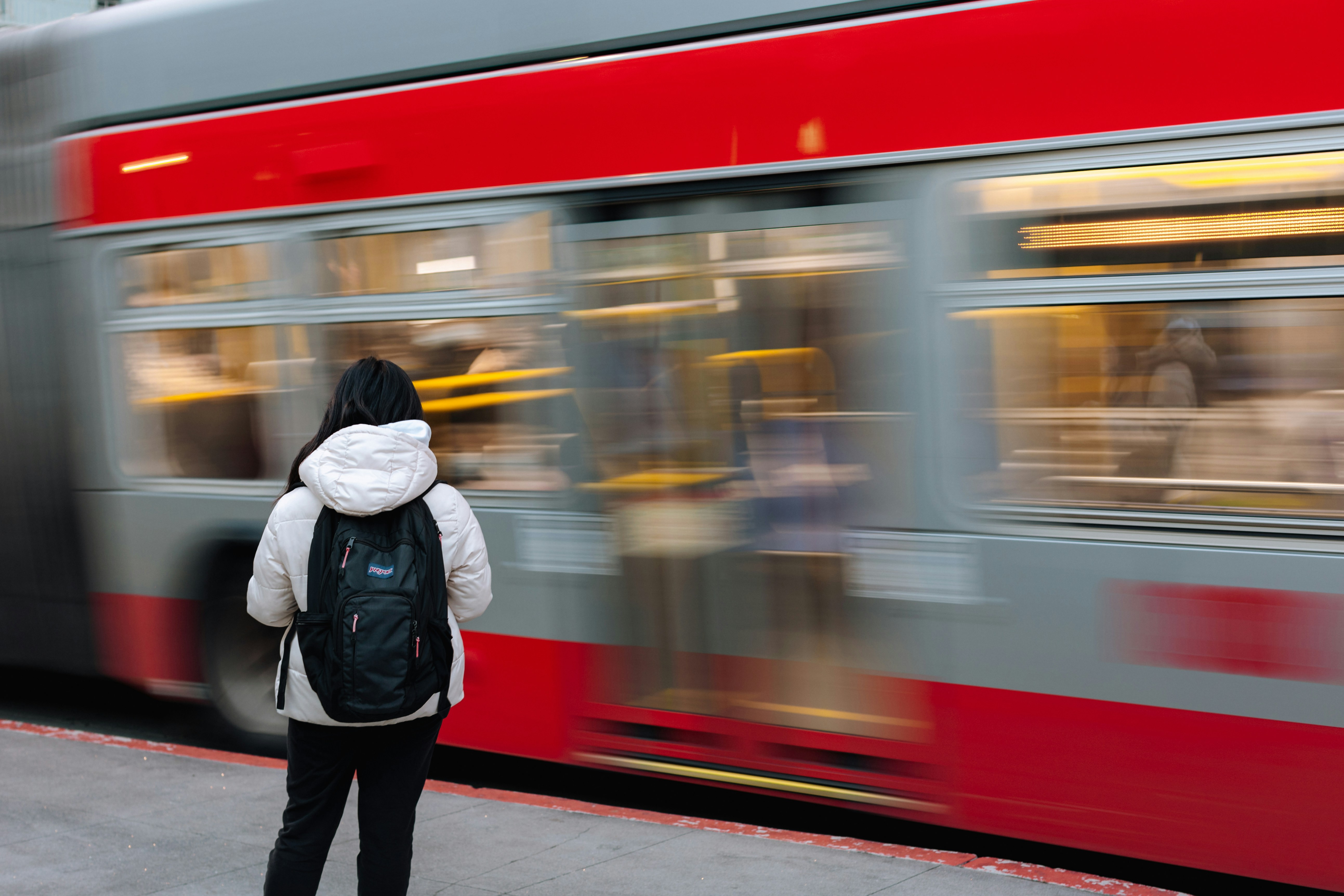 a person standing on a sidewalk next to a train