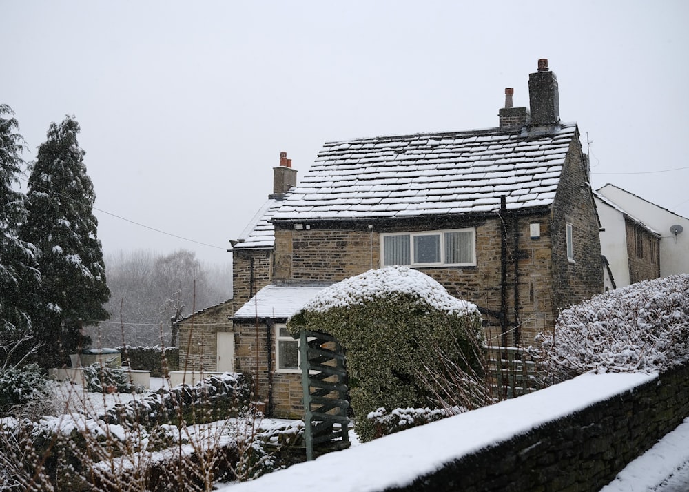 a house covered in snow next to a fence