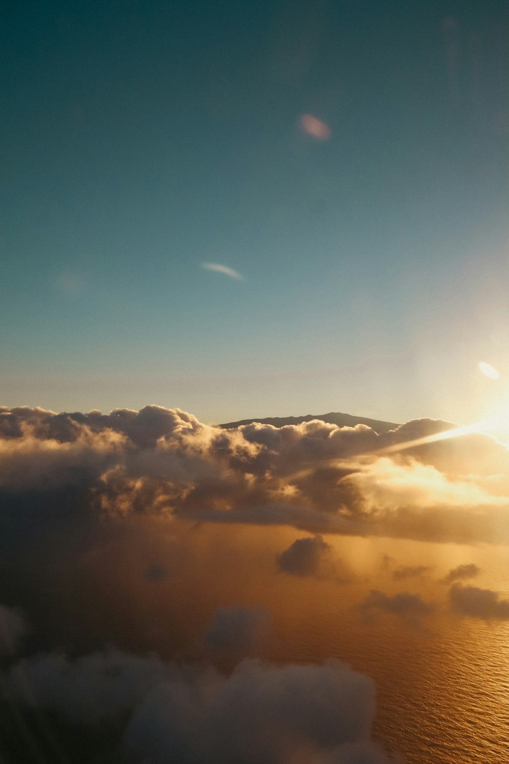 the sun shining through the clouds over the ocean