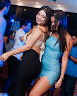 two young women are dancing at a party