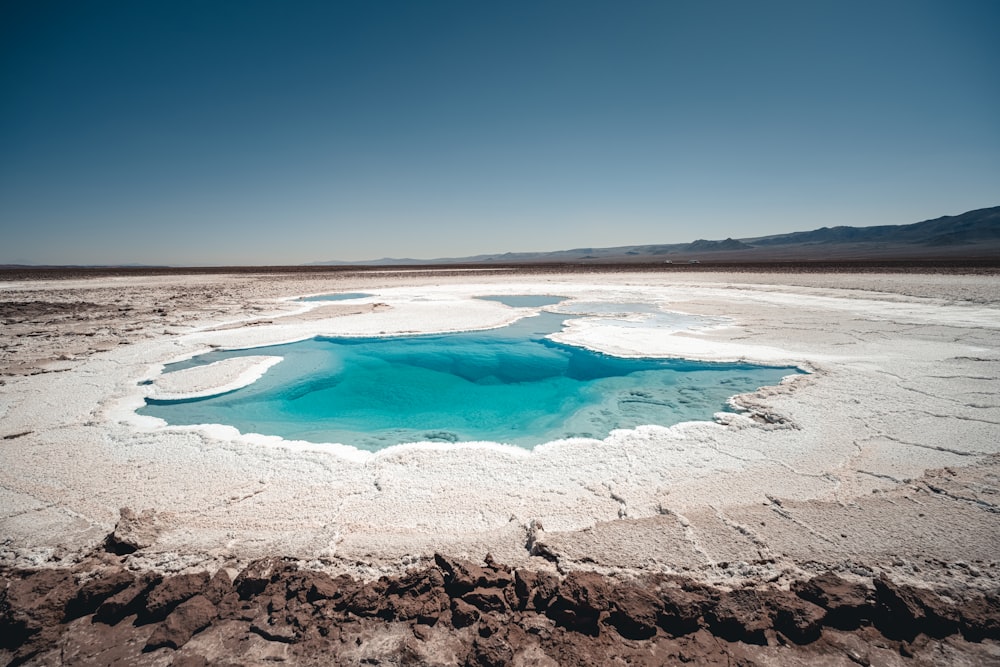 a blue pool of water in the middle of a desert