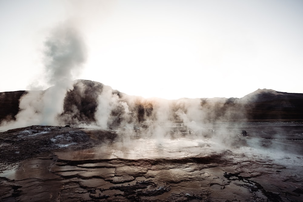 a geyser spewing water into the air with a mountain in the