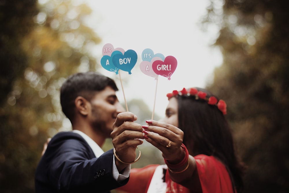 a man and a woman holding heart shaped balloons