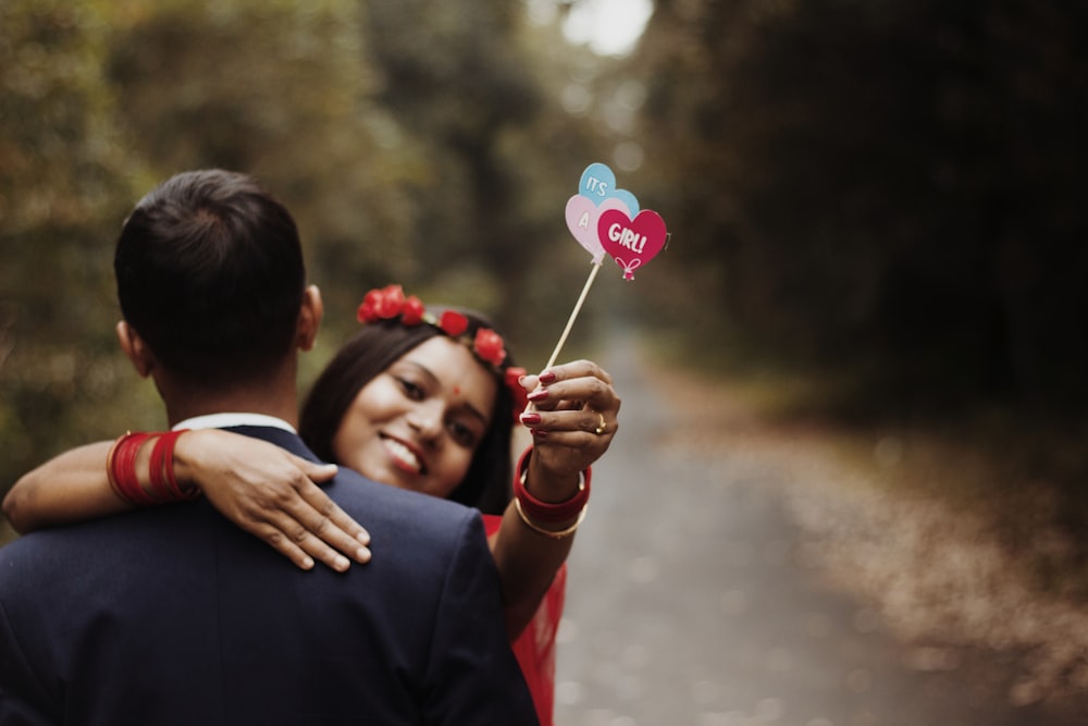 a man and a woman holding a heart shaped lollipop