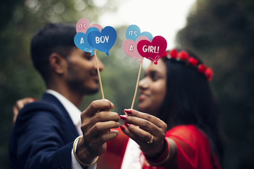 a man and a woman holding heart shaped balloons