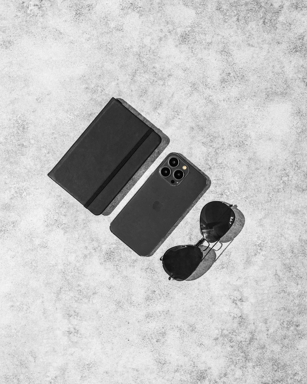 a black and white photo of a pair of sunglasses and an iphone