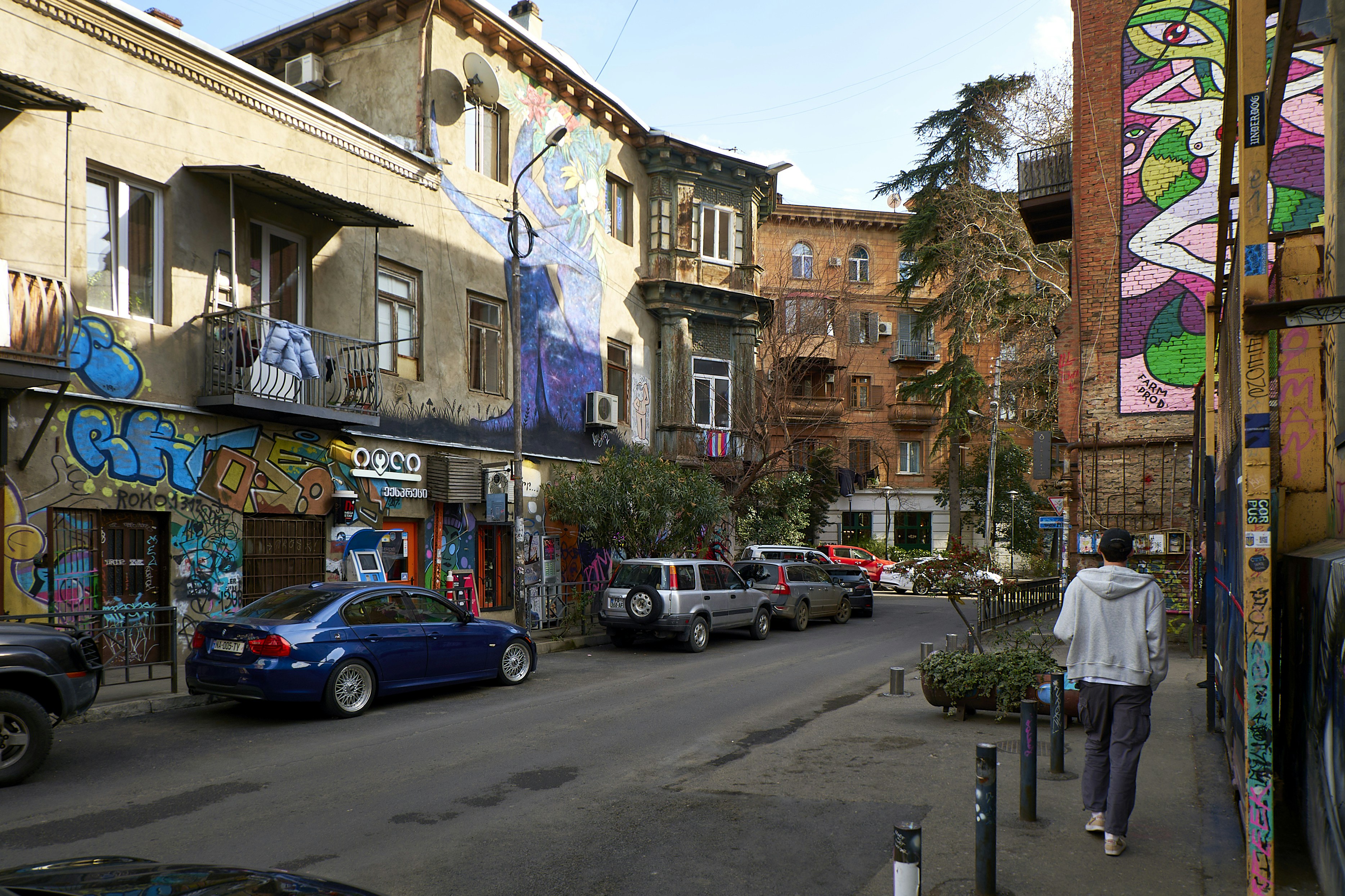 a man walking down a street next to parked cars