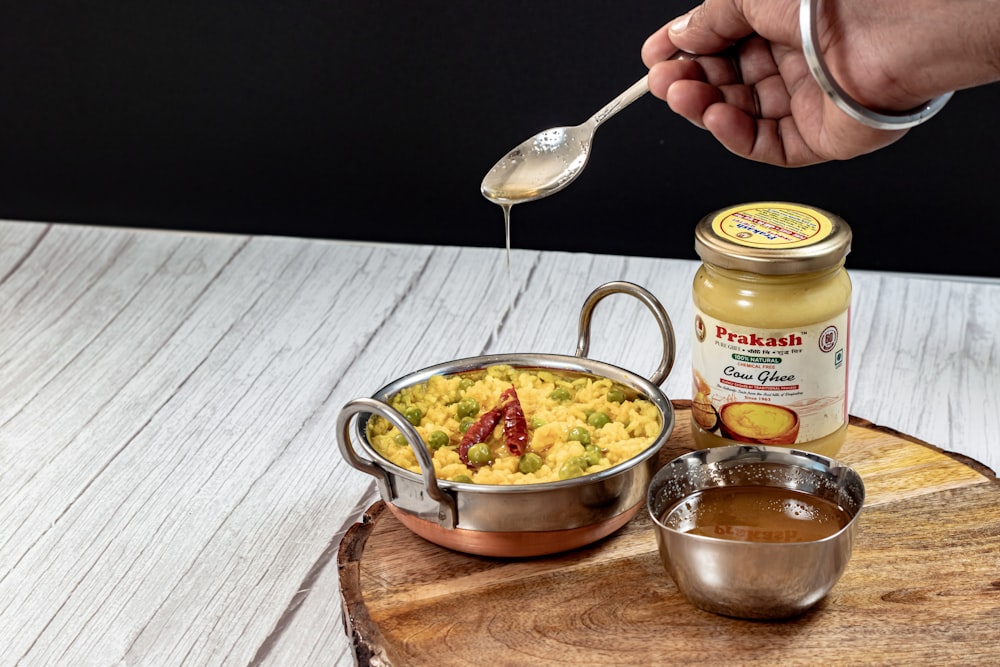 a person holding a spoon over a bowl of food