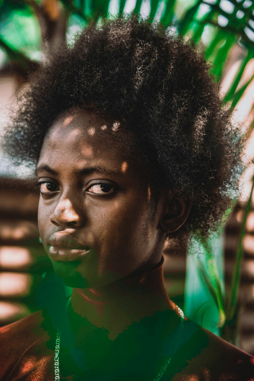 a woman with an afro standing in front of a palm tree