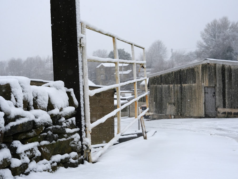 a fence is covered in snow next to a stone wall