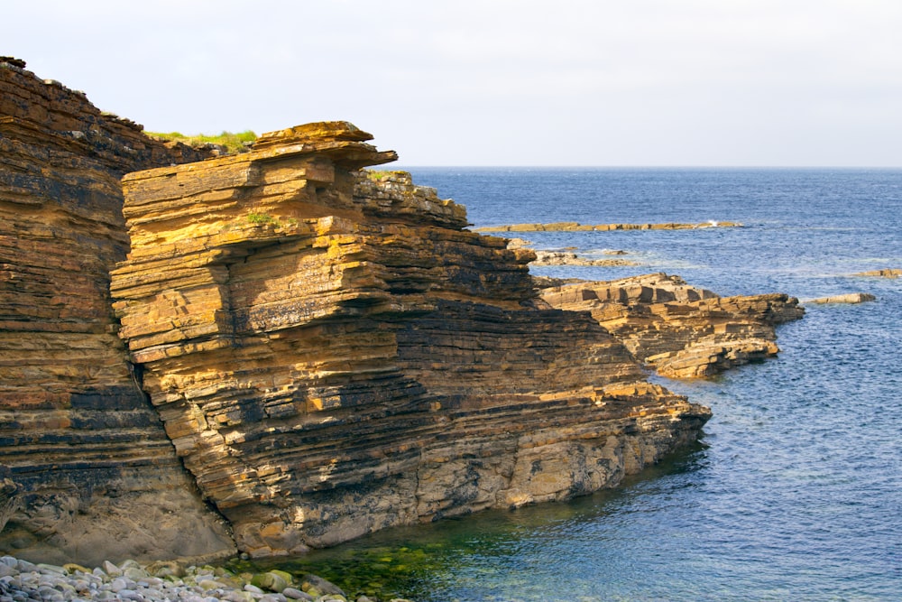 a rocky cliff next to a body of water