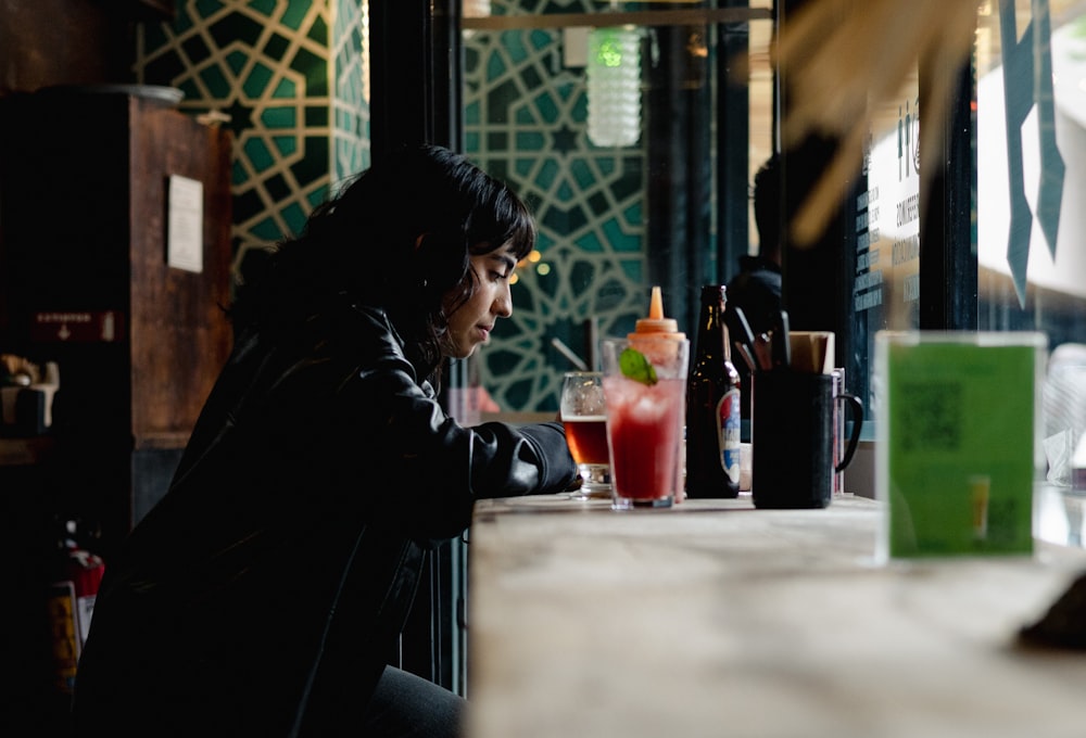 a woman sitting at a bar looking at her cell phone