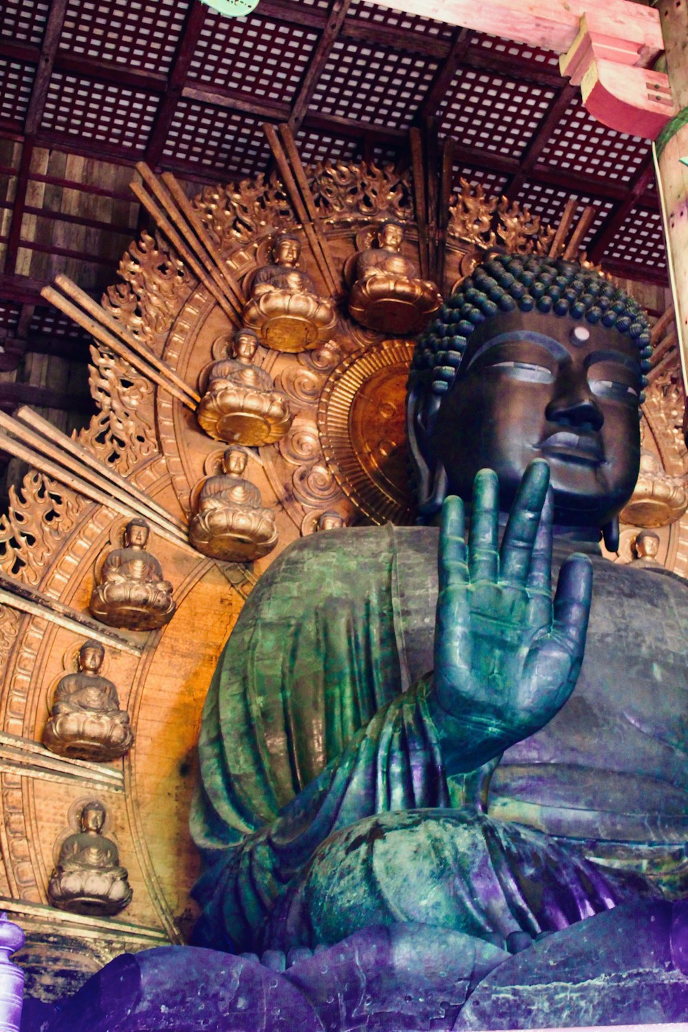 a large buddha statue sitting under a wooden ceiling