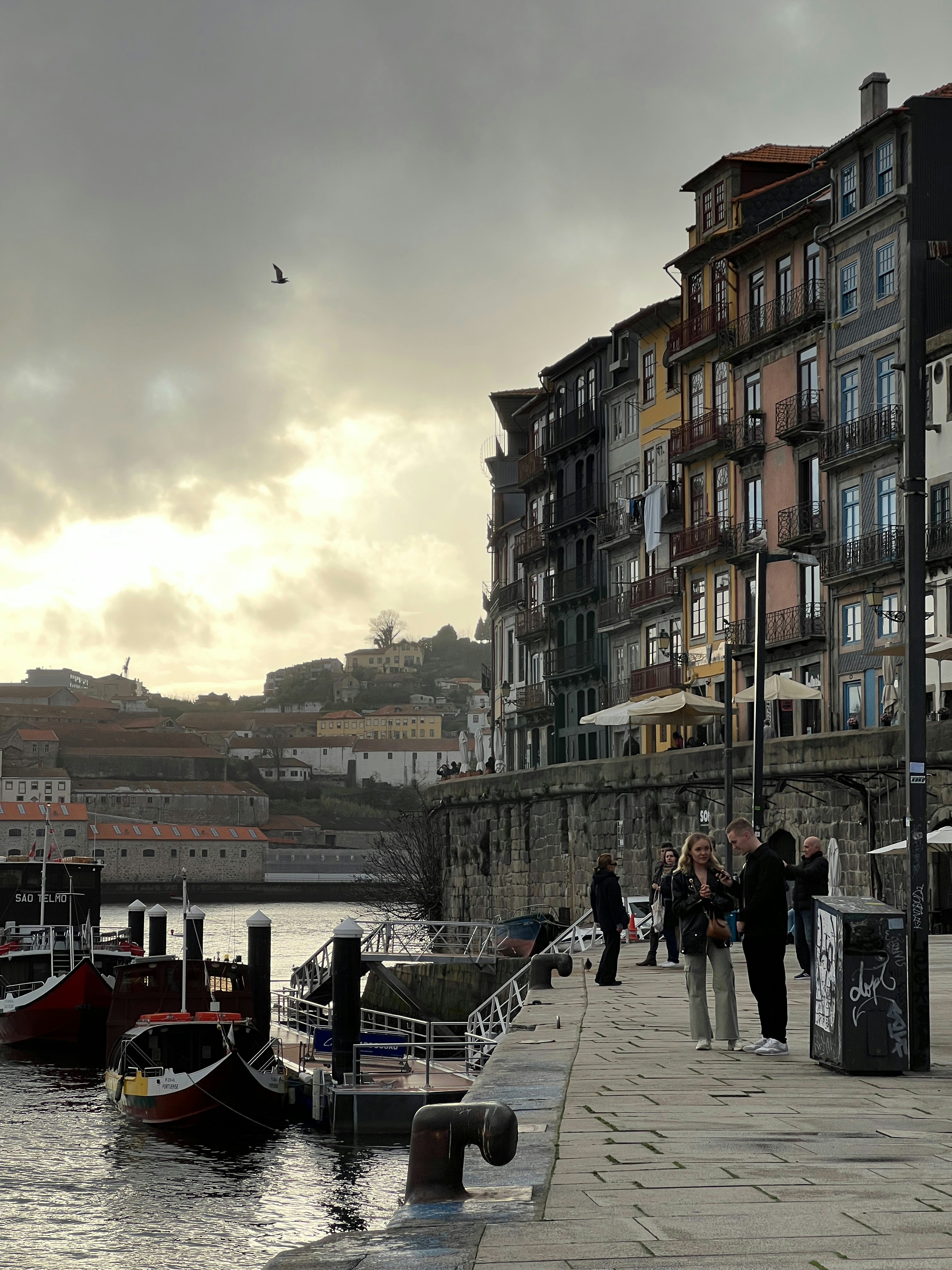 a group of people walking on a sidewalk next to a body of water