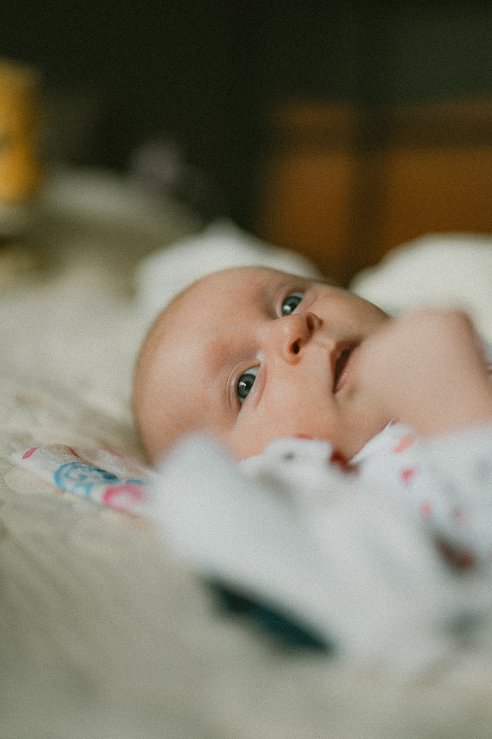 ein Baby, das mit einer Decke auf einem Bett liegt