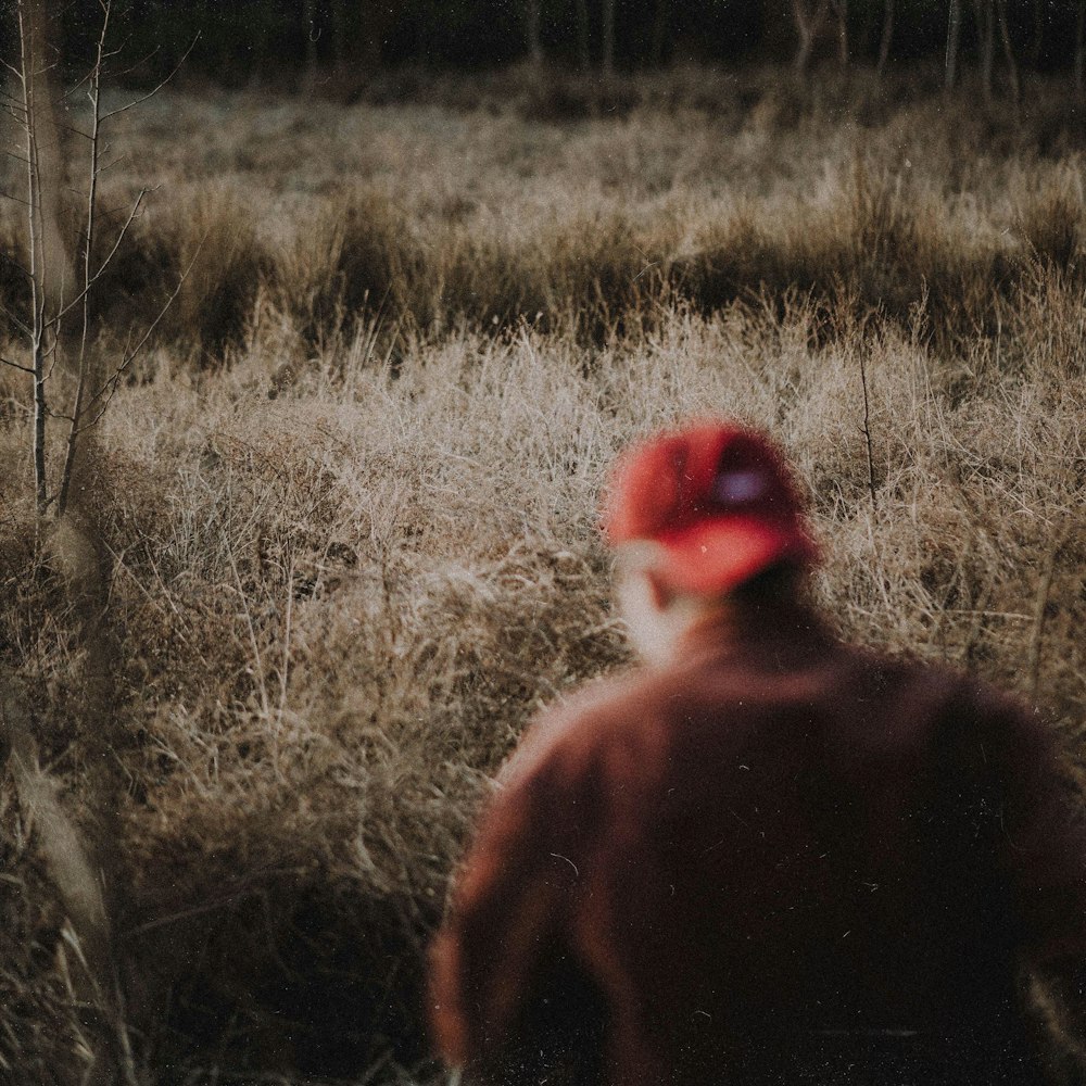 a man in a red hat walking through a field
