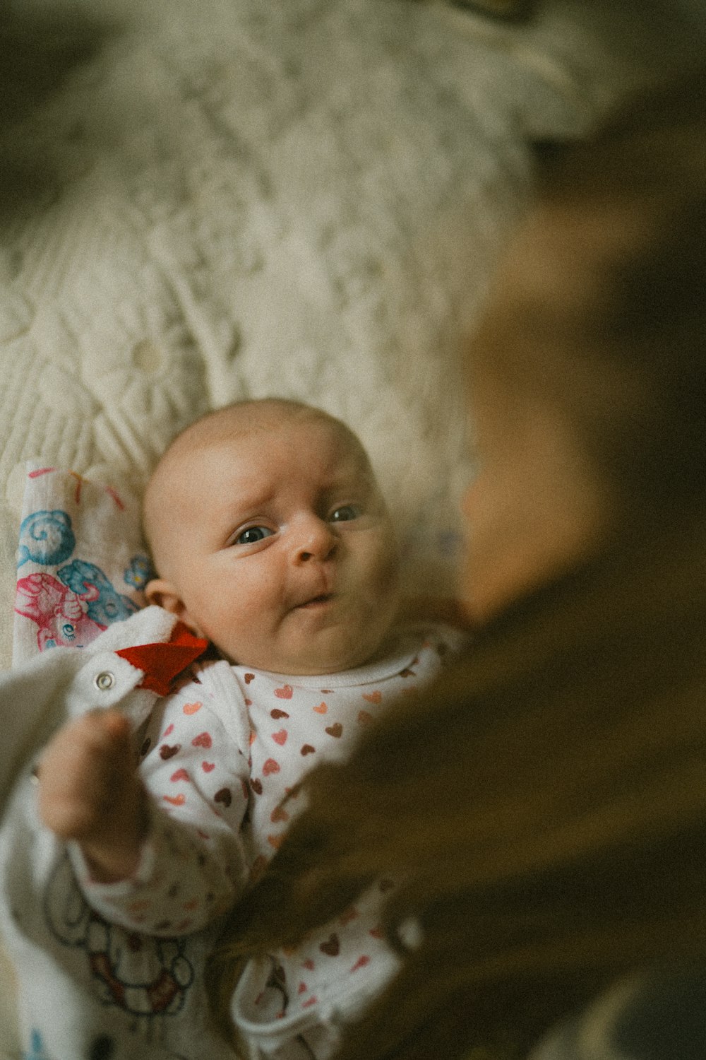 ein Baby, das neben einer Frau auf einem Bett liegt