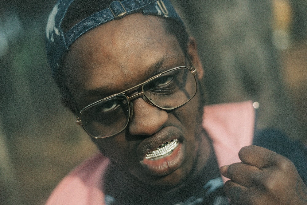 a man wearing glasses and a hat with a toothbrush in his mouth