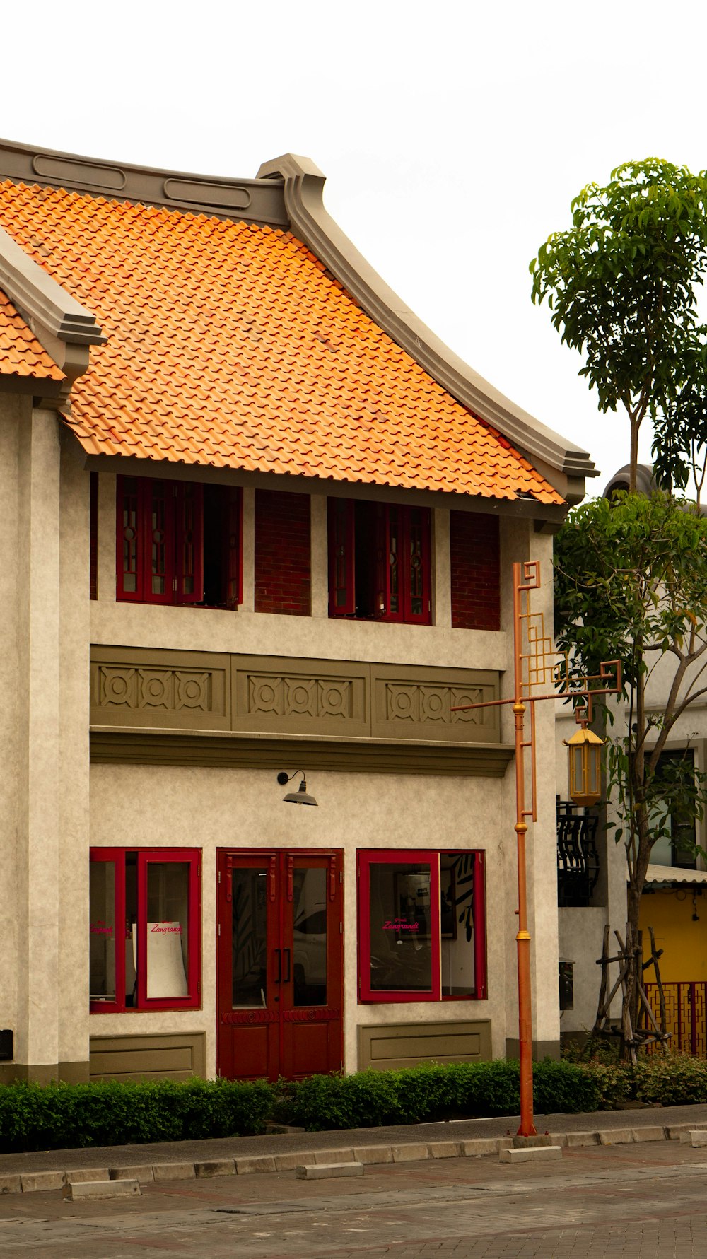 a white building with red shutters and a yellow roof