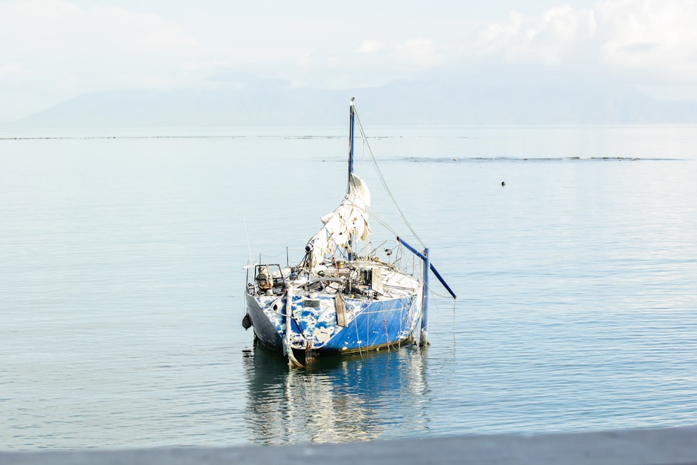 a blue and white boat floating on top of a body of water